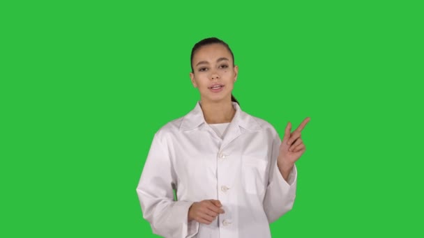 Médico atraente apontando para o lado apresentando o produto em uma tela verde, Chroma Key . — Vídeo de Stock