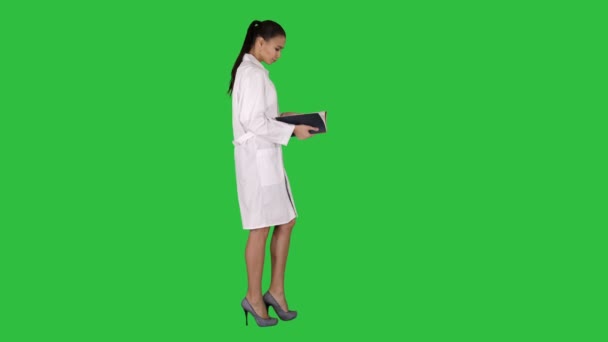 Attraktive Medizinstudentin oder Ärztin mit Notebook, das auf einem grünen Bildschirm läuft und liest, Chroma-Schlüssel. — Stockvideo