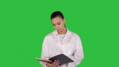 Orta atış. Genç kadın bir yeşil ekranda Chroma Key yürürken belgeleri okuma doktor. 4 k çözünürlüklü profesyonel vurulmuş. 013. sen-ebilmek kullanma o bir örneğin ticari video, işinizde