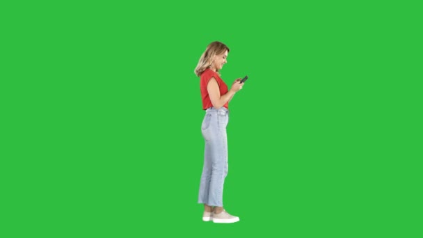 Lässige junge Frau tippt auf Handy auf grünem Bildschirm, Chroma-Schlüssel. — Stockvideo