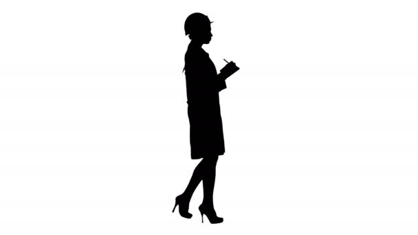 Silhouette Woman engineer with helmet is holding pen and checklist putting something down while walking. — Stock Video