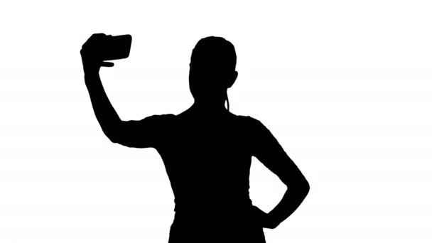 Silhouette Χαμογελώντας ελκυστική γυναίκα λαμβάνοντας μια selfie, ενώ το περπάτημα. — Αρχείο Βίντεο