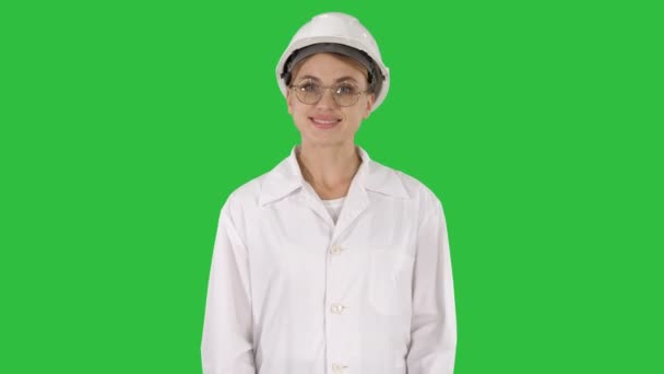 Profesionální žena v laboratorní plášť a bílé bezpečnostní přilba chůzi a usmívá se na zelené obrazovce, Chroma Key. — Stock video