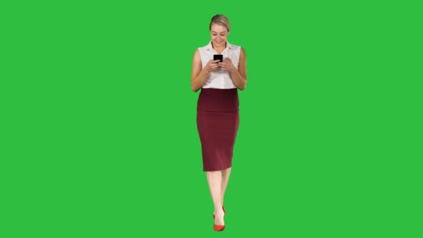 Empleadora exitosa escribiendo un mensaje de texto en su teléfono celular mientras camina en una pantalla verde, Chroma Key . — Vídeos de Stock