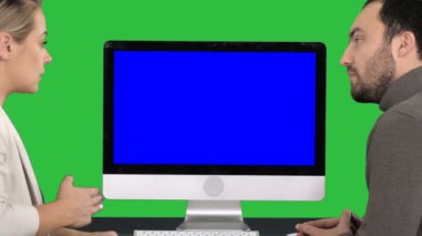 Bilgisayarı izlemek için arkadan görünüm. İş meslektaşlarımız bir adam ve bir kadın Chroma anahtar yeşil ekranda bilgisayarın ekranında nedir hakkında konuşmayı. Mavi ekran Mock-up