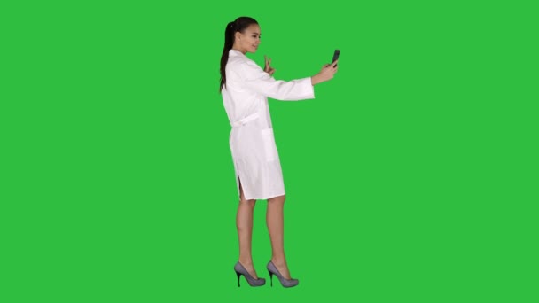 Elegante médico europeu morena tomando selfie no telefone enquanto caminha em uma tela verde, Chroma Key . — Vídeo de Stock
