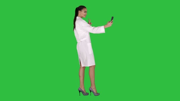 Elegant europeiska läkare brunett tar selfie på telefon medan promenader på en grön skärm, Chroma Key. — Stockvideo