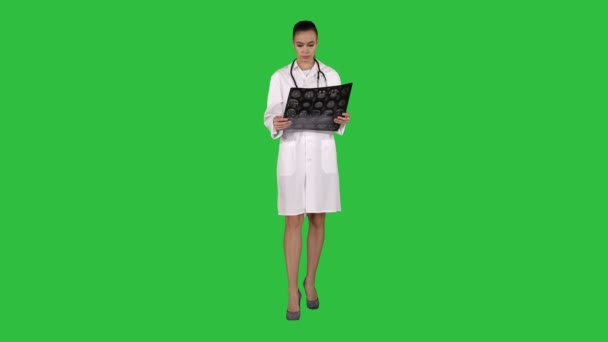 Vrouw van de dokter met witte labojas, kijken naar de radiografische image x-ray, ct-scan, mri op een groen scherm, Chromakey. — Stockvideo