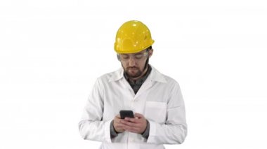 Koruyucu gözlüklü ve şapkalı bir mühendis, beyaz arka planda telefonla konuşuyor..