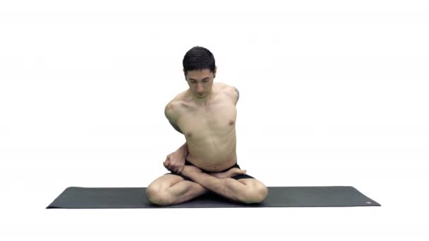 在Adho Mukha Padmasana，身材魁梧的年轻男子正在练习瑜伽，双腿交叉地坐在那里，弯腰在白色背景下变身成莲蓬形. — 图库视频影像