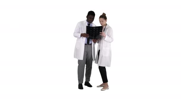 Ernsthafte schöne Frau Arzt und afroamerikanische Arzt Studie Gehirn-Röntgenbild auf weißem Hintergrund. — Stockvideo