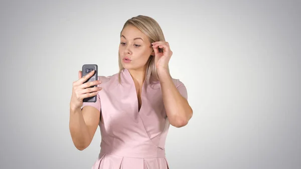 Hermosa rubia cabeza dama haciendo videollamada utilizando el teléfono celular en el fondo gradiente . —  Fotos de Stock