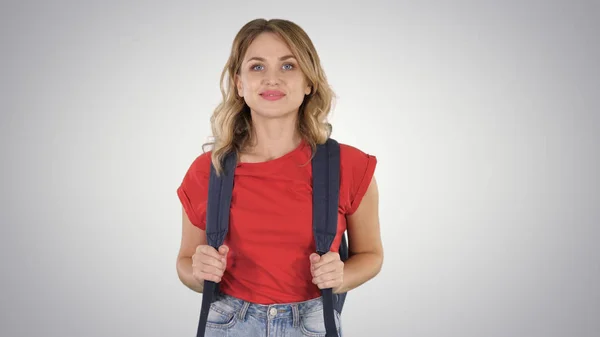 Ung snygg kvinna i casual T-shirt med ryggsäck och jeans gå på tonad bakgrund. — Stockfoto