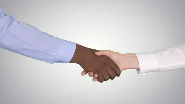 Handshake de afro-americano e caucasiano mãos femininas sobre fundo gradiente . — Fotografia de Stock