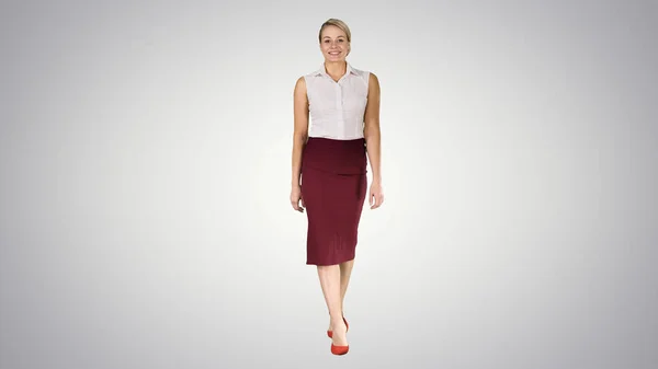 Cantik sexy brunette wanita bisnis gaya kantor fashion pakaian berjalan dan tersenyum ke kamera di latar belakang gradien . — Stok Foto