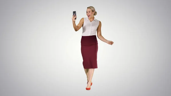 步行妇女在梯度背景下使用智能手机进行视频通话. — 图库照片