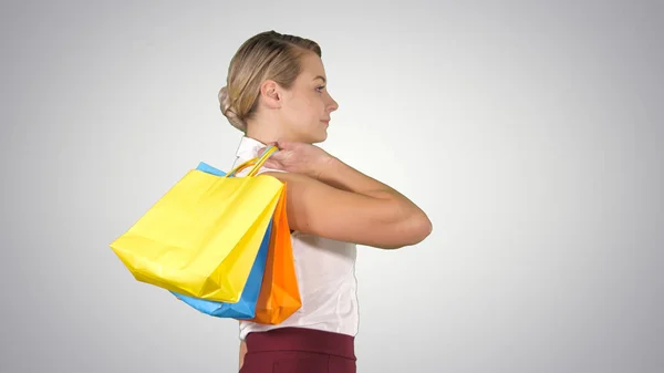 Joven mujer feliz con bolsas de compras caminando sobre fondo degradado . —  Fotos de Stock