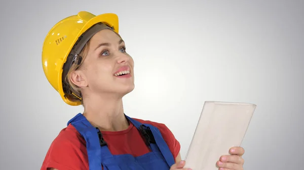 Engenheira de construção feminina com um computador tablet em um canteiro de obras em fundo gradiente . — Fotografia de Stock