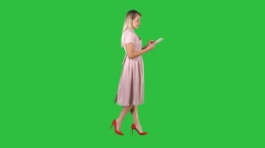 Pembe elbise sarışın yürüyüş ve tablet Chroma anahtar yeşil ekran kullanma.