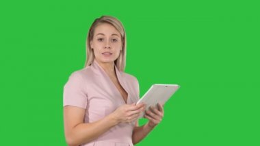 Dijital tablet kullanma ve Chroma anahtar yeşil ekran kameraya konuşurken güzel kadın.