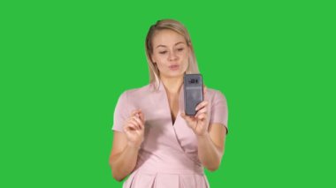 Güzel sarışın baş Bayan Chroma anahtar yeşil ekran cep telefonu kullanarak görüntülü arama yapma.