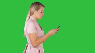 Pembe elbise manifatura Chroma anahtar yeşil ekranda akıllı telefon üzerinde güzel kadın.