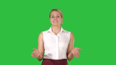 Neşeli genç güzel kadın kamera için Chroma anahtar yeşil ekran yürürken söz.