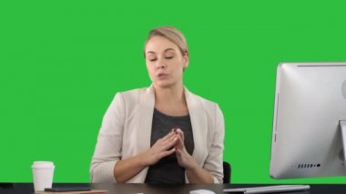 Bayan arıyorum ve çalışma masasında kameraya konuşurken ve yeşil ekran, Chroma Key tarafta işaret.