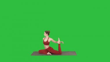 Güzel genç kadın giyiyor kırmızı spor Yoga ya da pilates yapıyor egzersiz bir bacaklı Kral güvercin poz, Eka Pada Rajakapotasana Chroma anahtar yeşil ekranda.