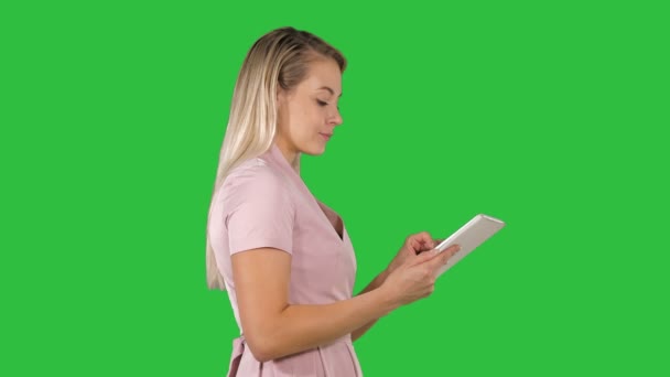 Schöne Frau benutzt ein Tablet und geht auf einem grünen Bildschirm, Chroma-Taste. — Stockvideo