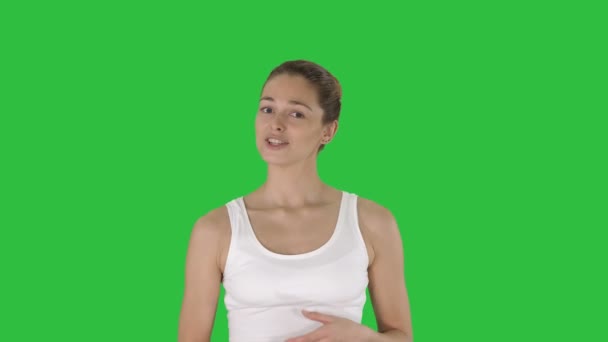 Vrouw in witte boven iets uit te leggen tijdens het lopen op een groen scherm, Chromakey. — Stockvideo