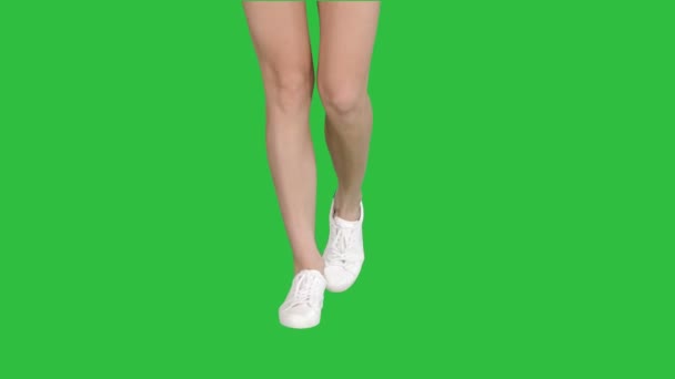 Vrouwelijke benen in witte sneakers lopen op een groen scherm, Chromakey. — Stockvideo