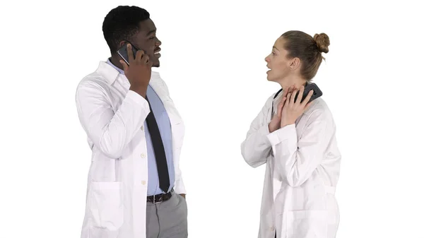 Médico feminino e masculino usando telefones celulares fazendo chamadas contando notícias felizes no fundo branco. — Fotografia de Stock