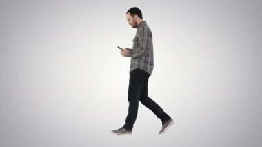 Yürüyüş ve degrade arka plan üzerinde cep telefonuyla mesaj okuma genç smart casual adam.
