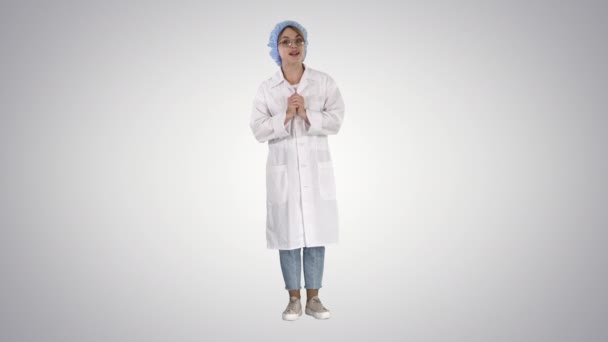 Smiling cute medical doctor woman talking to camera on gradient background. — Stock Video