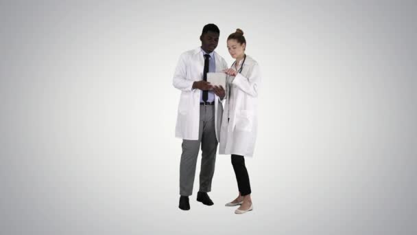 Intellektuelle Gesundheitsexperte afroamerikanischer Arzt mit Kollegen mit digitalem Tablet auf Gradienten-Hintergrund. — Stockvideo