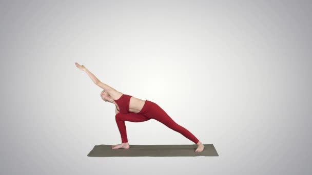Mladá žena cvičí jógu, dokončí cvičení Utthita parsvakonasana na sklonu pozadí. — Stock video