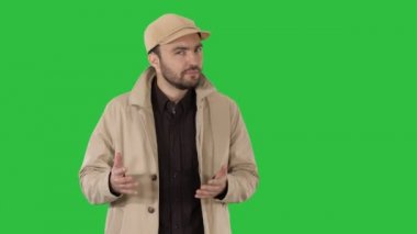 Yürüyüş ve Chroma Key bir yeşil ekran üzerinde kamera söyleyerek kendine güvenen genç yakışıklı adam.