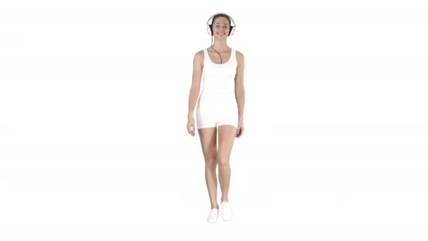 Charmante fille de fitness marchant et écoutant de la musique sur fond blanc .