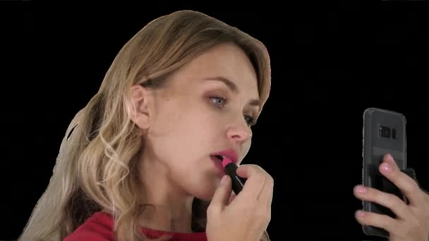 Hermosa mujer joven con estilo aplicando lápiz labial rojo en los labios y mirando a la pantalla del teléfono, Alpha Channel — Vídeo de stock