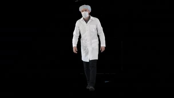 Maskeli ve tıbbi şapkalı yürüyen genç erkek doktor, Alfa Kanalı. — Stok video