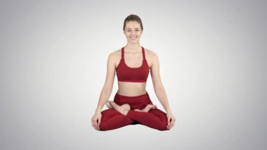 Kadın pratik yoga, gülümseyen genç Padmasana yaparken egzersiz, Lotus poz degrade arka plan üzerinde.