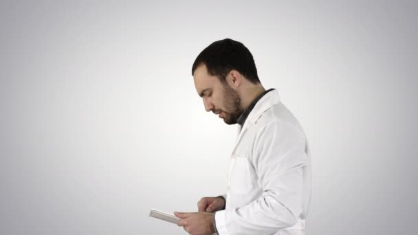 Retrato del médico varón caminando y usando tableta digital sobre fondo de gradiente . — Vídeo de stock
