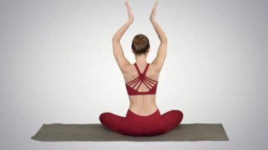 Lotus poz, birleştirme Eller başının üzerinde gradyan arka planı üstünde oturan genç sportif kadın.