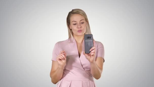 Hermosa rubia cabeza dama haciendo videollamada utilizando el teléfono celular en el fondo gradiente . — Vídeo de stock