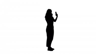 Tam yol ileri. Yan görüş. Siluet kadın ruj kullanıyor ve telefonuna bakıyor. 4K çözünürlükte profesyonel atış. 006. Kullanabilirsin, mesela. Ticari videonuzda, işinizde, sunumunuzda