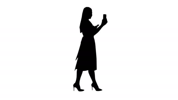 完全な長さの肖像画側のビュー シルエット歩いている間にスマートフォンの録画ビデオブログを使用してピンクのホールディングの若い女性 4K解像度でのプロのショット 2005年 使用することができます 君の中で — ストック動画
