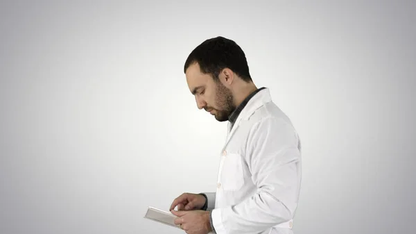 Portret lekarza Mężczyzna spaceru i za pomocą cyfrowego tabletu na tło gradientowe. — Zdjęcie stockowe