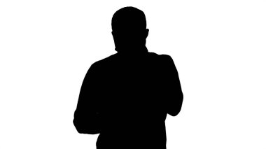 Siluet Üzgün genç adam yürüyor ve elinde yüzüyle cep telefonuna bakıyor.