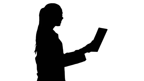 Silhouette Jeune femme médecin tenant la tablette dans ses mains et faisant un appel vidéo . — Photo